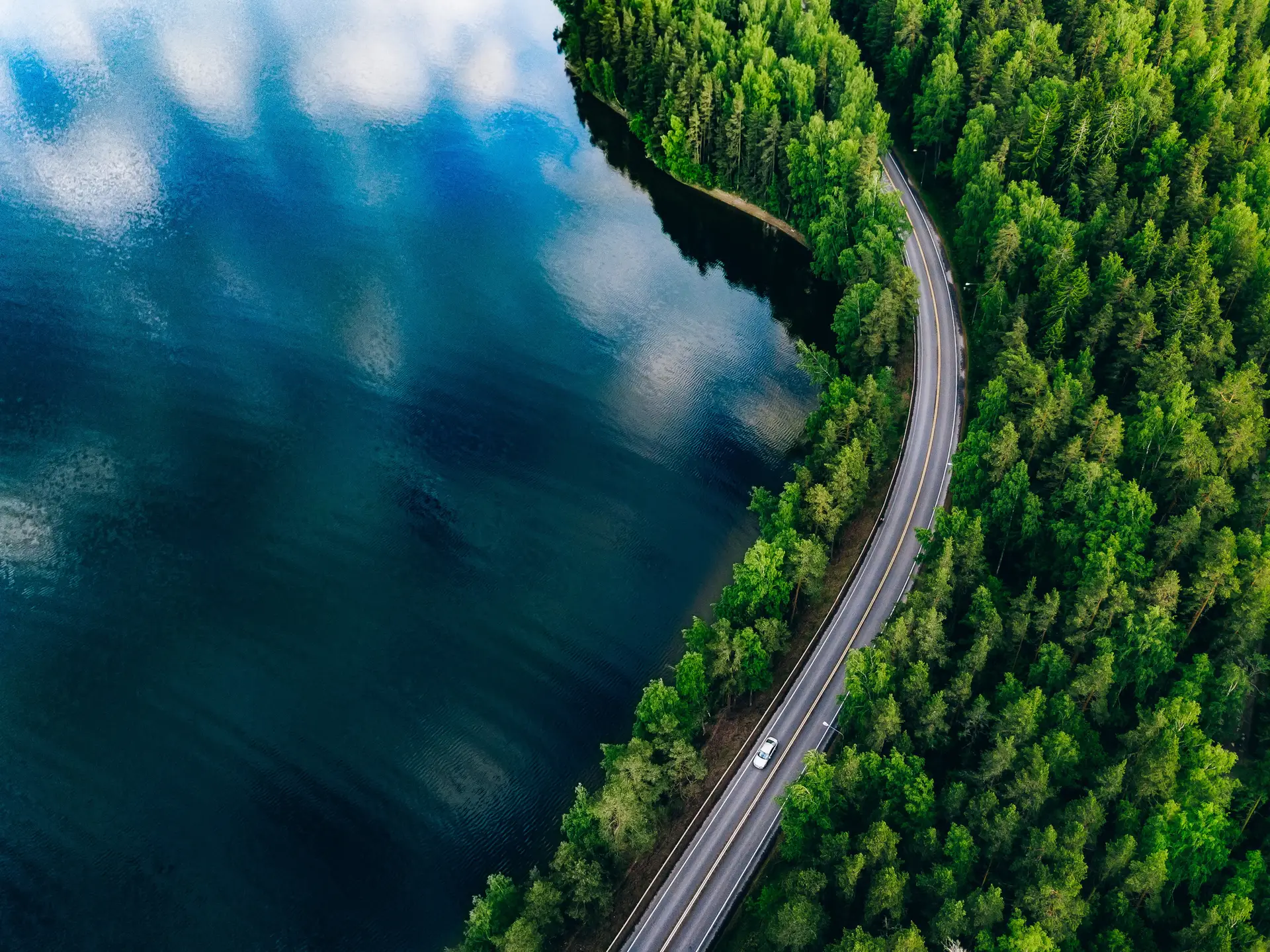Aerial road between forest and lake representing scalable hydrogen infrastructure